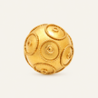 A gold-colored spherical ring with raised circular medallion details and rope-like borders, photographed on a clean off-white background.